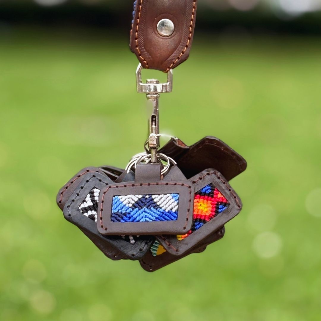 Handcrafted custom dog ID tag with woven pattern and leather trim, silver swivel clip close-up hanging on strap